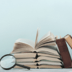 Stack of books with a magnifying glass.