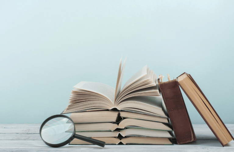 Stack of books with a magnifying glass.